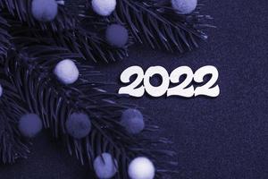 tarjeta de Navidad. flatley ramas de un árbol de navidad juguetes de piel de colores y el número 2022 sobre un fondo muy peri. foto