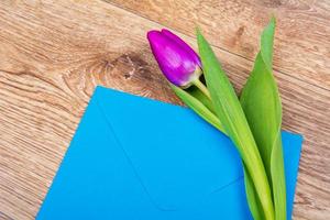 Blue envelope with tulips on a table photo