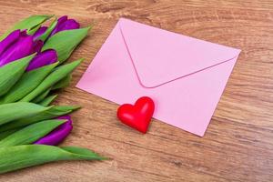 Pink envelope with tulips on a table photo