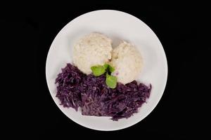 Tempeh with red cabbage and sorghum on a black photo