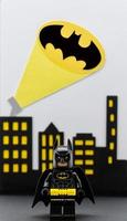 Bologna, Italy, 2021 - Lego Batman miniature against Gotham City background. Batsignal from the rooftops. photo