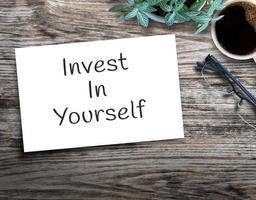 Text sign showing Invest In Yourself. on wood table photo