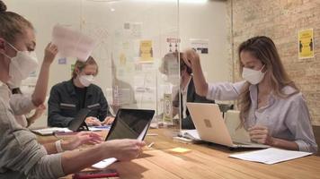 Multiracial business coworker team working in a new normal office. COVID-19 protection by cleared partition workplace, social distancing, and face mask for pandemic health and disease prevention. video