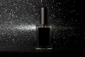 Perfume glass bottle on black glitter background, shiny copy space photo