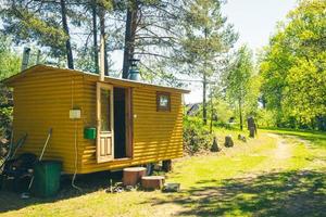 Cabina de sauna de madera amarilla al aire libre con la puerta abierta y no hay gente en el campo verde naturaleza al aire libre foto