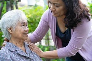 Caregiver daughter help Asian senior or elderly old lady woman on electric wheelchair in park. photo