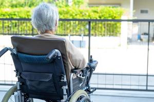 Paciente asiático mayor o anciano en silla de ruedas eléctrica con control remoto en la sala del hospital de enfermería, concepto médico fuerte y saludable foto