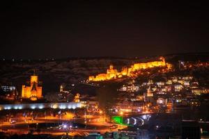 Panoramic night view old Tbilisi with snowy mountains and Illuminated city sreets