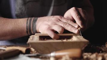 El tallador procesa la tabla de madera de roble con un cuchillo.