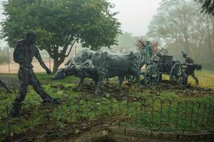 Bento Goncalves, Brazil - July 14, 2019. Bronze statues of people and ox cart at the Immigrant Monument in a foggy day at Bento Goncalves. A friendly country town famous for its wine production. photo