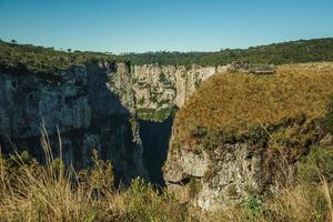 Cambara do Sul, Brazil - July 16, 2019. People at wooden belvedere on the edge of cliff at the Itaimbezinho Canyon near Cambara do Sul. A small country town with amazing natural tourist attractions. photo
