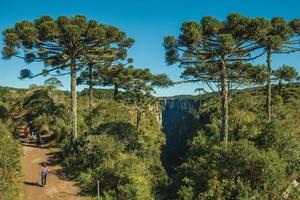 Cambara do Sul, Brazil - July 16, 2019. Dirt pathway and people at the Itaimbezinho Canyon with rocky cliffs near Cambara do Sul. A small country town with amazing natural tourist attractions. photo