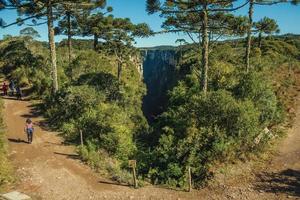 Cambara do Sul, Brazil - July 16, 2019. Dirt pathway and people at the Itaimbezinho Canyon with rocky cliffs near Cambara do Sul. A small country town with amazing natural tourist attractions. photo