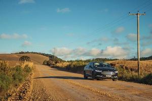 Cambara do Sul, Brazil, July 17, 2019. Car on dirt road passing through rural lowlands called Pampas with dry bushes near Cambara do Sul. A small rural town with amazing natural tourist attractions. photo