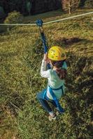 Bento Goncalves, Brazil - July 11, 2019. Girl descending by cable in a zip-line over meadows and trees on a valley near Bento Goncalves. A friendly country town famous for its wine production. photo