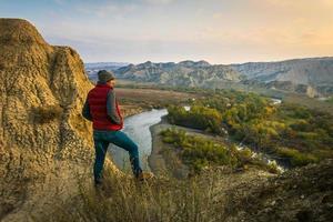 Male person stands on the edge and look right to sunrise with stunning landscape view of Mijniskure. Vashlovani nature reserve photo