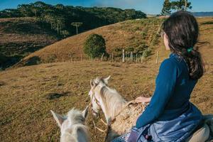 cambara do sul, brasil - 18 de julio de 2019. chica a caballo en un paisaje de tierras bajas rurales con colinas llamadas pampas cerca de cambara do sul. un pequeño pueblo rural con increíbles atractivos turísticos naturales. foto