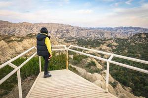 Brunette woman stands on the platform viewpoint and looks over beautiful landscape of Vashlovani nature reserve photo