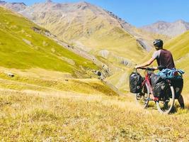 vista posterior ciclista empujar bicicleta de turismo cuesta arriba a la montaña. ruta de senderismo en bicicleta del paso de atsunta