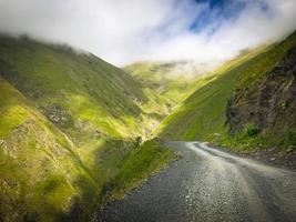 Pintoresco camino de ripio de montaña en la región de Tusheti rodeado por la naturaleza neblinosa del Cáucaso foto