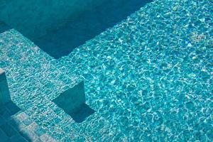 Detalle de una hermosa escalera en piscina azul. escalera bajo el agua azul clara baja a la piscina al aire libre, escalones a la piscina, parte cercana de la piscina, escalones bajo el agua. foto
