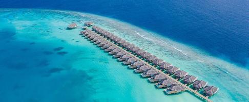 Perfect aerial landscape, luxury tropical resort or hotel with water villas and beautiful beach scenery. Amazing bird eyes view in Maldives, landscape seascape aerial view over a Maldives photo
