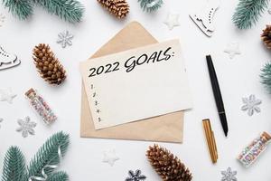 Top view of 2022 goals on sheet of paper and pen with envelope on table with winter decor photo