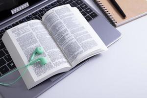 Open Bible and laptop on the work table with headphones. Bible Study Online photo