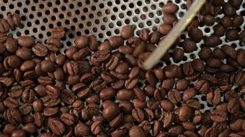 Close-up de granos de café recién tostados de un gran tostador de café en la máquina de refrigeración de mezcla café industrial