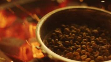 Proceso de tostado de granos de café con sartén pequeña en una fábrica de tostadoras quemando procesos de enfriamiento quema de llama de bebidas video