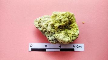 Sulphur mineral stone isolated on pink background. Hand specimen from The Dieng volcanic complex,   hydrothermal activity in the form of hot water photo