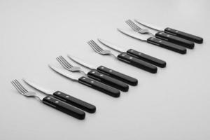 tenedores y cuchillos en una fila sobre un fondo claro foto