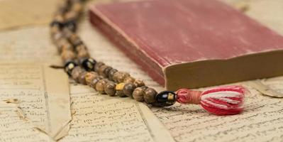Muslim prayer beads with Quran and with sheets with ancient Arabic scripts. Islamic and Muslim concepts photo