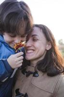 un niño le da una flor a su madre foto