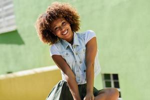 Young black woman, afro hairstyle, smiling in urban background photo