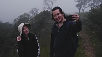 parejas de blogueros de turistas asiáticos que utilizan una cámara de acción para grabar el viaje y hablar sobre las atracciones turísticas en las montañas. viajes al aire libre y tema de la naturaleza. video