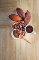 Hot cocoa cup with cocoa powder and cocoa beans on wooden background photo