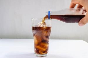 Vaso de refrescos y refrescos negros sobre la mesa. foto