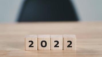 comienzo al año 2022. bloque de cubo de madera con texto del año 2022 en la mesa de madera con espacio de copia. concepto de feliz año nuevo. foto