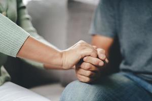 Amiga o familia sentada y tomarse de las manos durante la alegría del hombre depresivo mental, el psicólogo brinda ayuda mental al paciente. concepto de salud mental ptsd foto