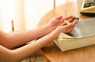 una adolescente sostiene una cruz cristiana en sus manos. concepto de esperanza, fe, cristianismo, religión, iglesia en línea. foto
