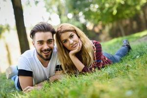 hermosa joven pareja tendido sobre el césped en un parque urbano. foto