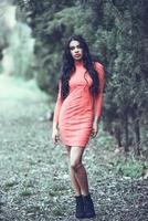 Hispanic young woman wearing orange dress in urban park photo