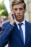 atractivo joven empresario por teléfono en el fondo urbano