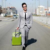 Man dressed in suit and suitcase walking along the street photo