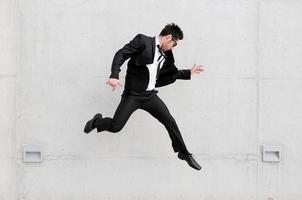 Young handsome businessman with eyeglasses jumping in the street photo