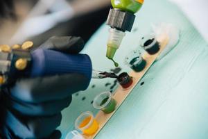 Female tattooist loading the tattoo machine with ink. photo