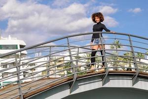 Afro hairstyle woman on roller skates riding outdoors on urban bridge photo