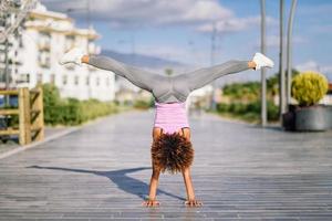 Black fit woman doing fitness acrobatics in urban background photo