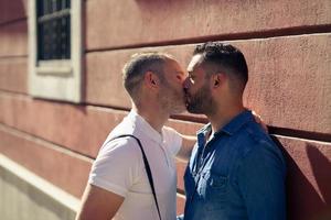 Gay couple kissing outdoors in urban background.